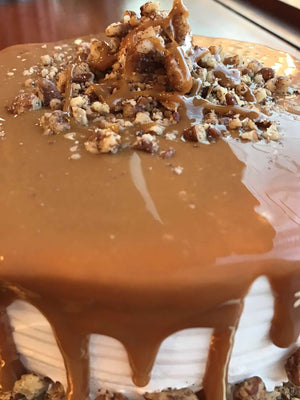 This ice cream cake is smothered in a cloak of delicious caramel that spills over the edges and meets crush pecans along the bottom of the cake. On top of the caramel pool is a generous portion of more chopped pecans and an additional drizzle of caramel.